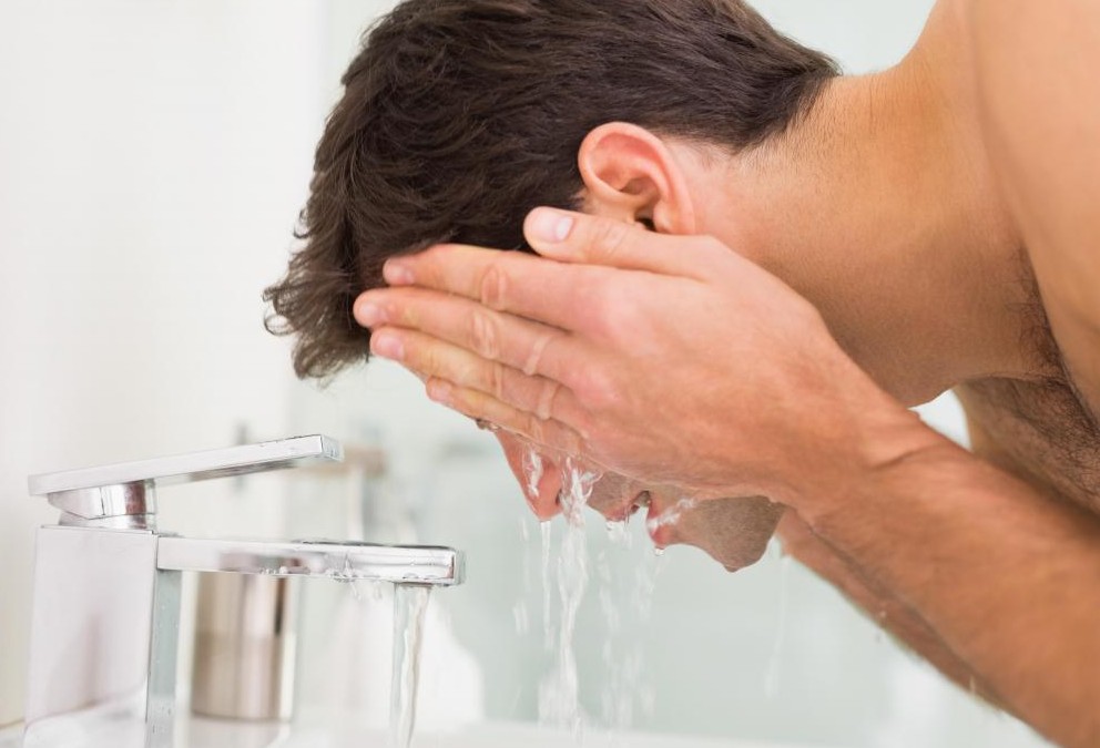 Man With Black Hair Washing His Face Near Sink E1436340575455