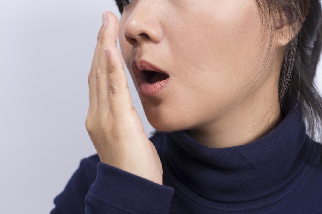 Woman Checking How Her Breath Smells By Holding Her Hand In Front Of Her Mouth