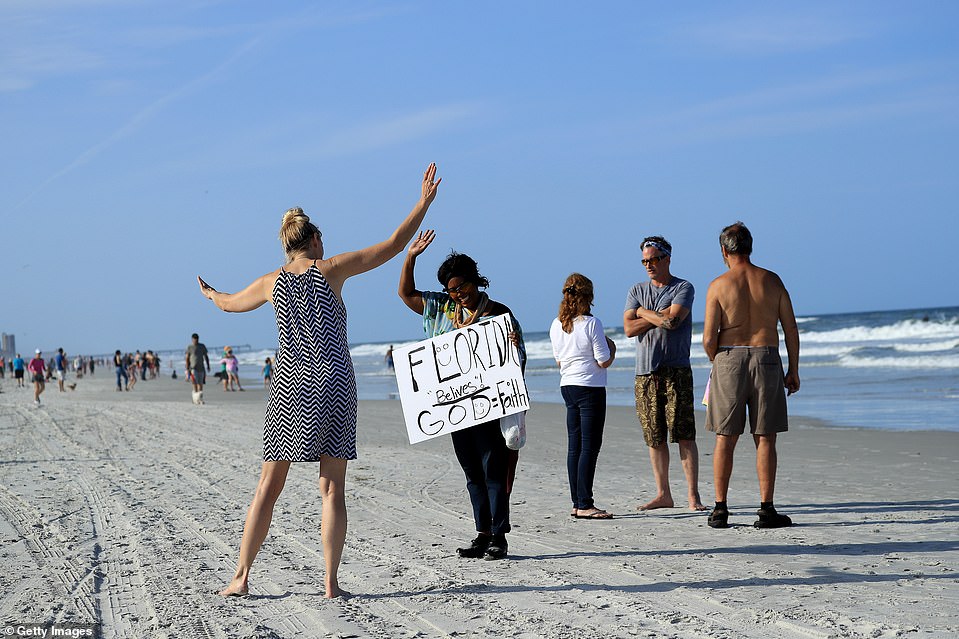 27339736 8229933 A_person_caries_a_sign_at_the_beach_on_Friday_in_Jacksonville_Be A 18_1587195036195