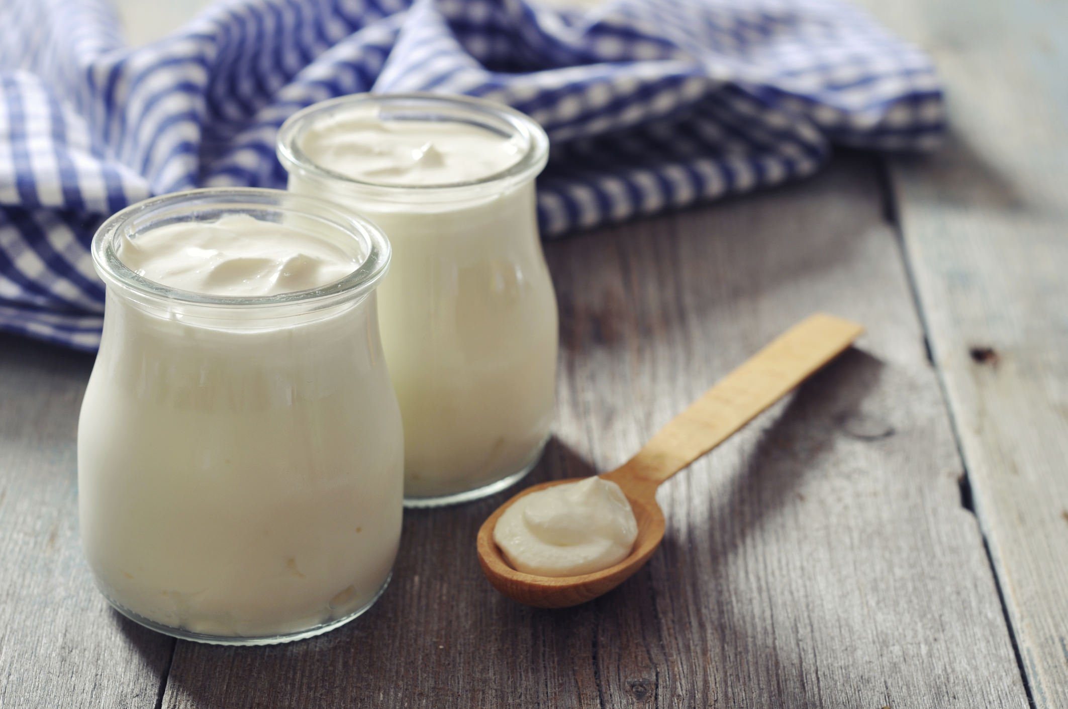 Greek Yogurt In Glass Jars With Wooden Spoon On Wood Table
