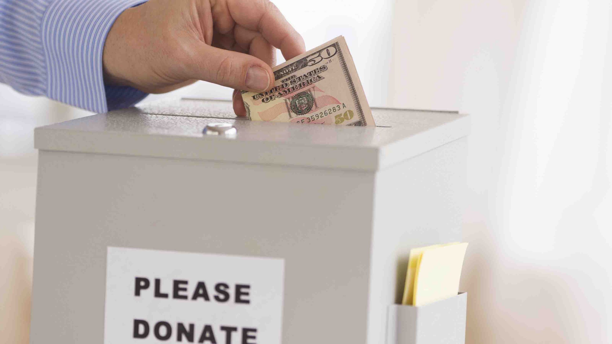 Jersey City, New Jersey, Man's Hand Putting Dollars Into Donation Box