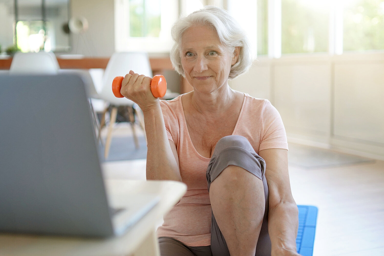 Senior Woman Doing Fitness Exercises At Home Through Virtual Cla