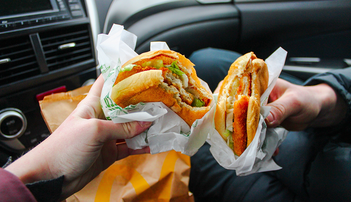 Cropped Image Of Hands Holding Hamburger In Car